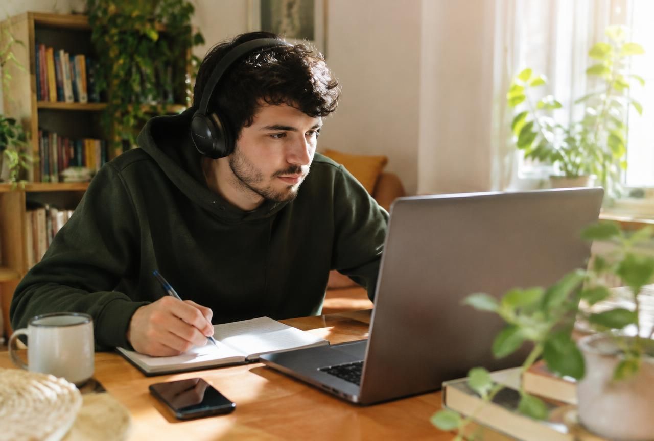 Learner taking notes while following an online lesson on a laptop